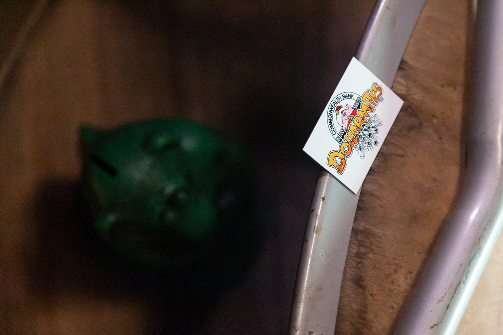 a white business card with a cartoon character of a yellow creature and words that read 'Dollarmites' is attached to the edge of an old school chair.